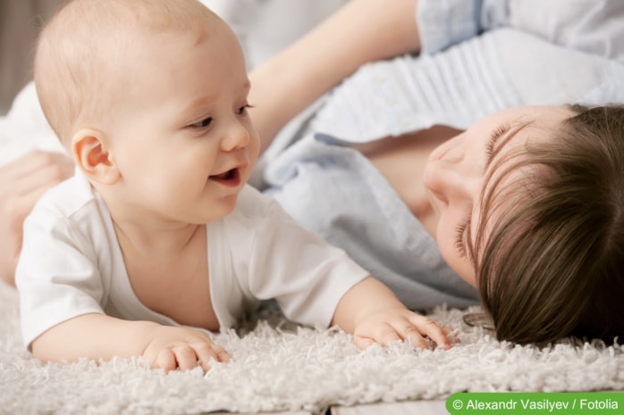 Baby mit Mutter auf Teppich